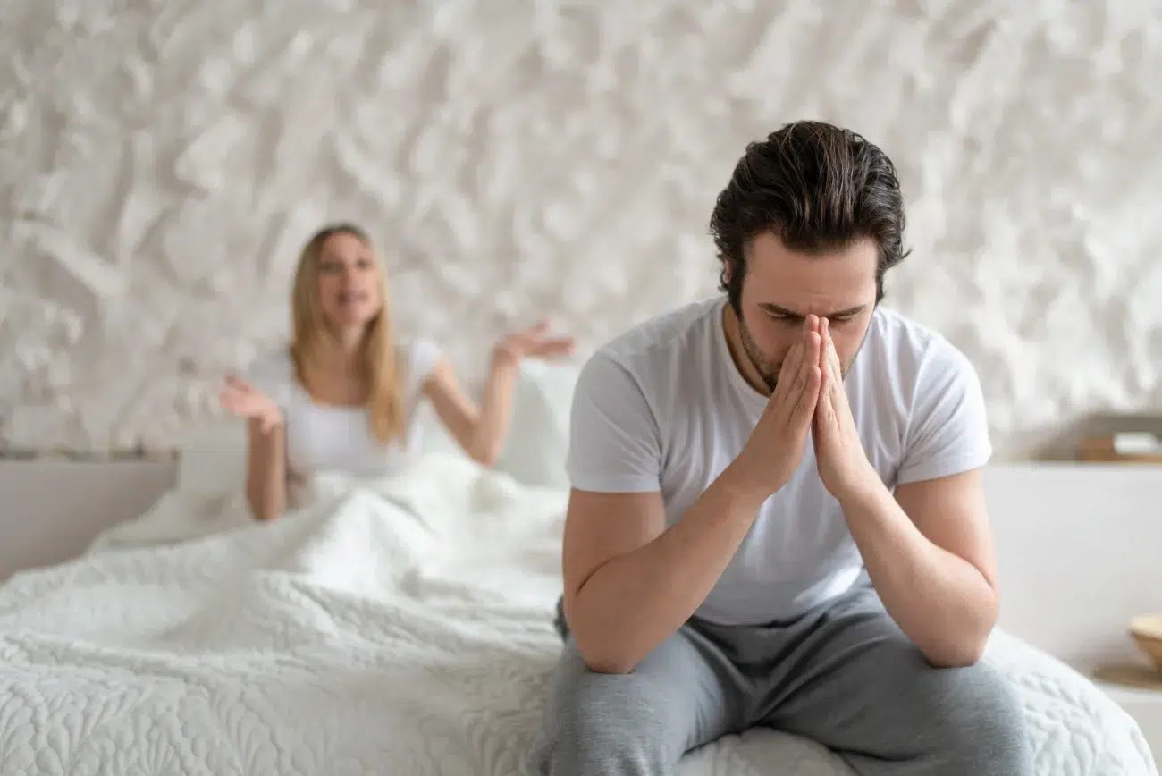 man upset over libido problems with wife sitting on edge of bed man upset over libido problems with wife sitting on edge of bed