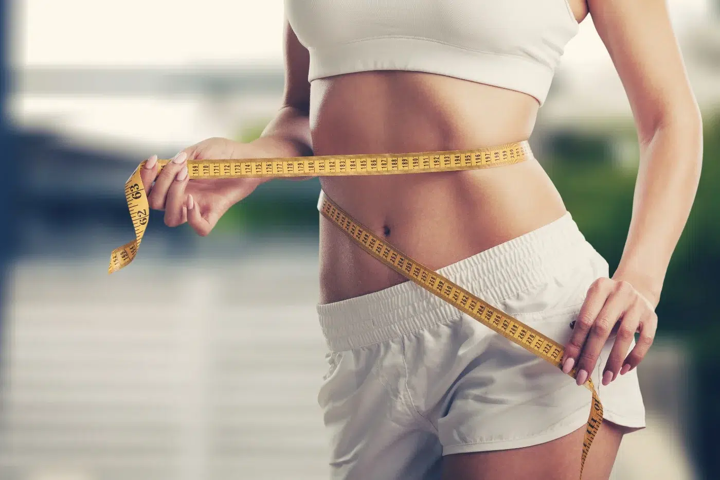woman with tape measure around waist showing weight loss