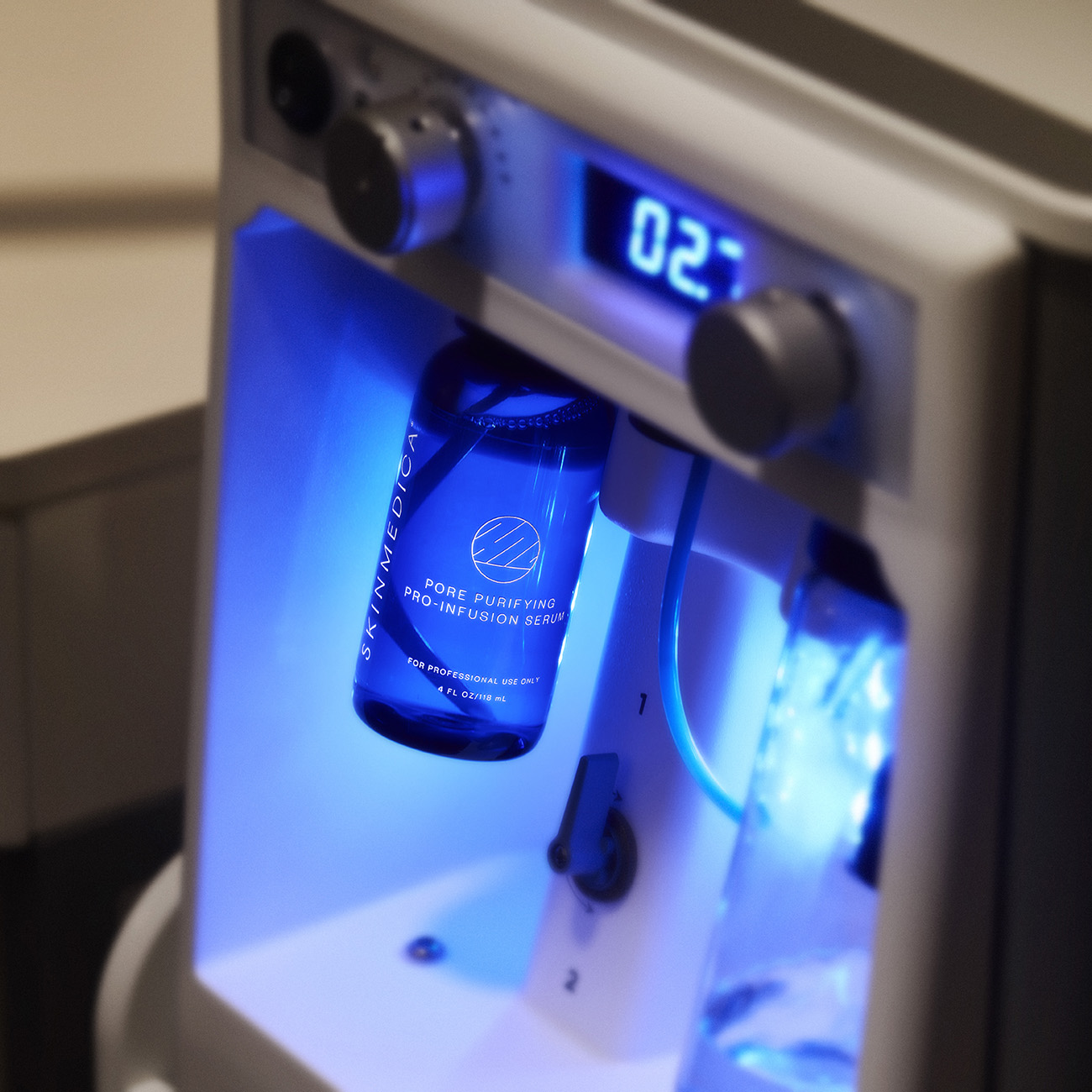 SkinMedica Pore Purifying Pro-Infusion Serum bottle in a blue-lit spa device.