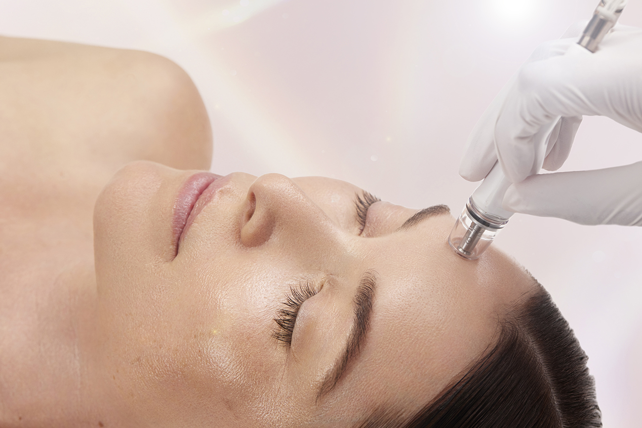 Woman receiving a professional facial treatment with a skincare device.